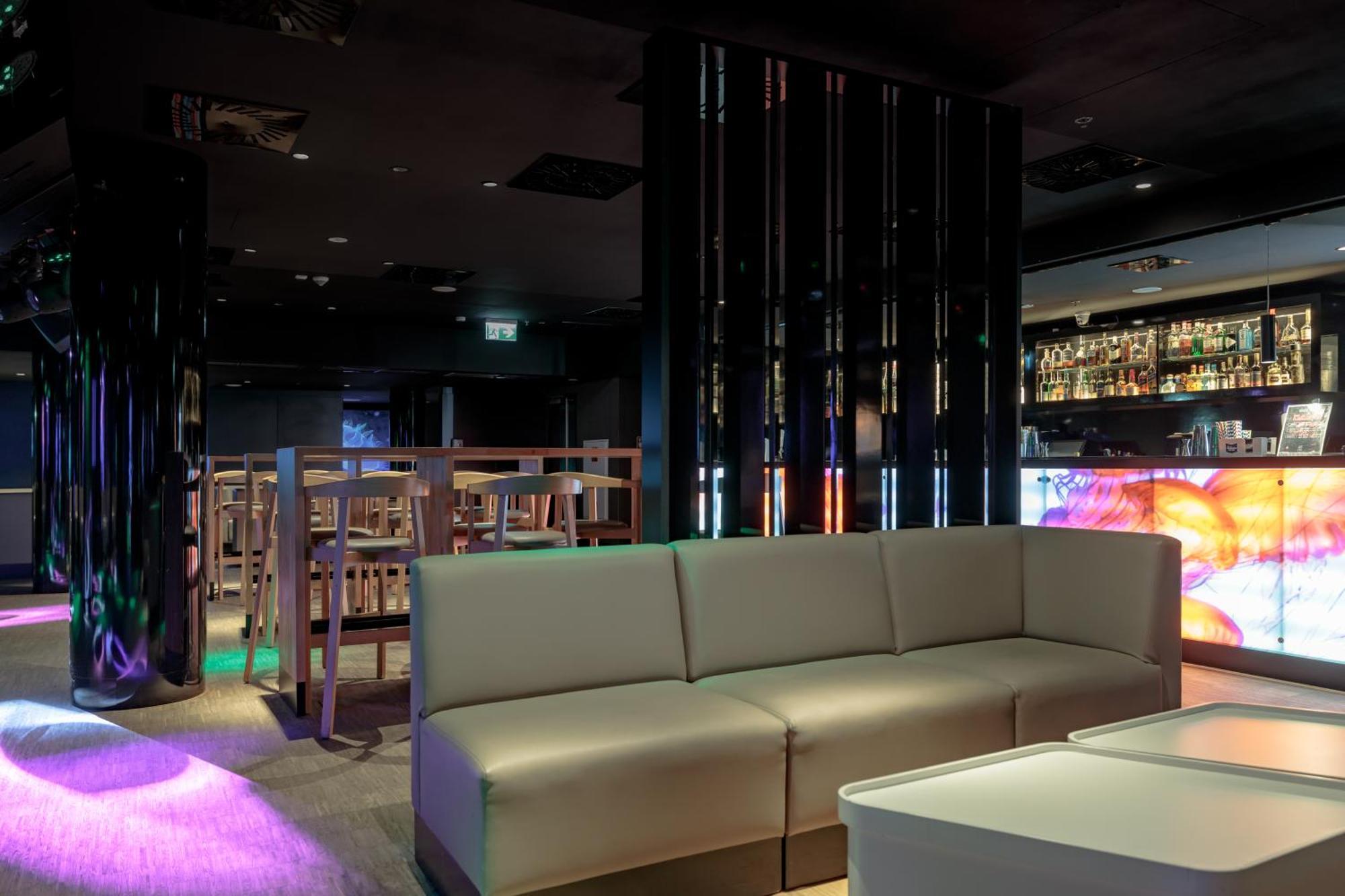 Radisson Blu Resort Swinoujscie Luaran gambar The photo shows the interior of a stylish lounge or bar. The space features a modern design with dark walls and a sleek atmosphere. There is a beige sectional sofa in the foreground, providing a casual seating area. In the background, a bar is visibl