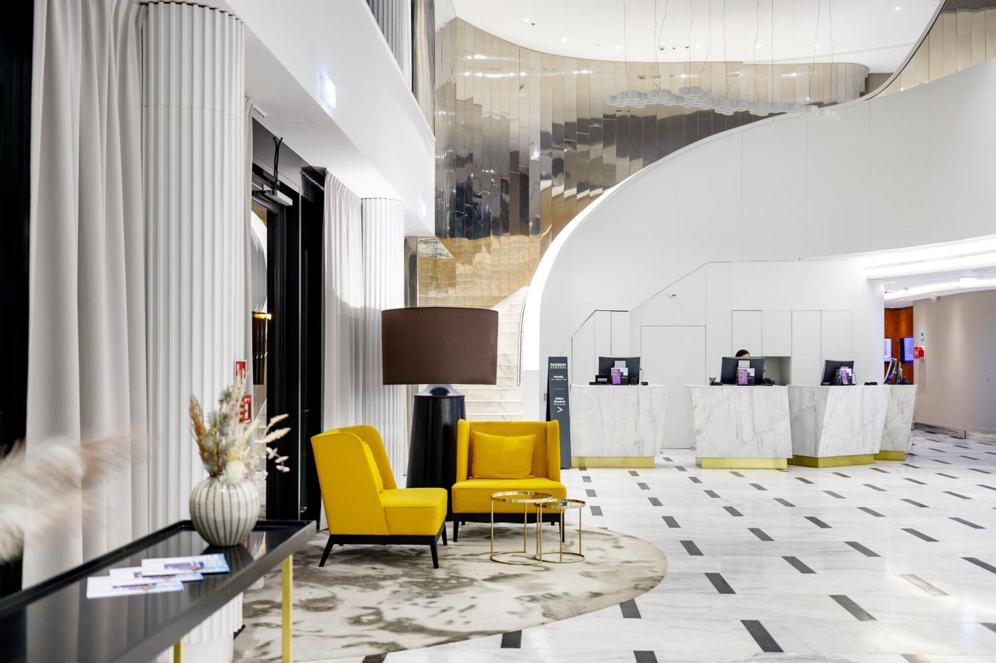 Radisson Blu Resort Swinoujscie Luaran gambar The photo shows the interior of a modern hotel lobby. The space features a stylish design with a combination of yellow and neutral-colored seating, including two yellow armchairs and a small table. In the background, there is a reception area with ma