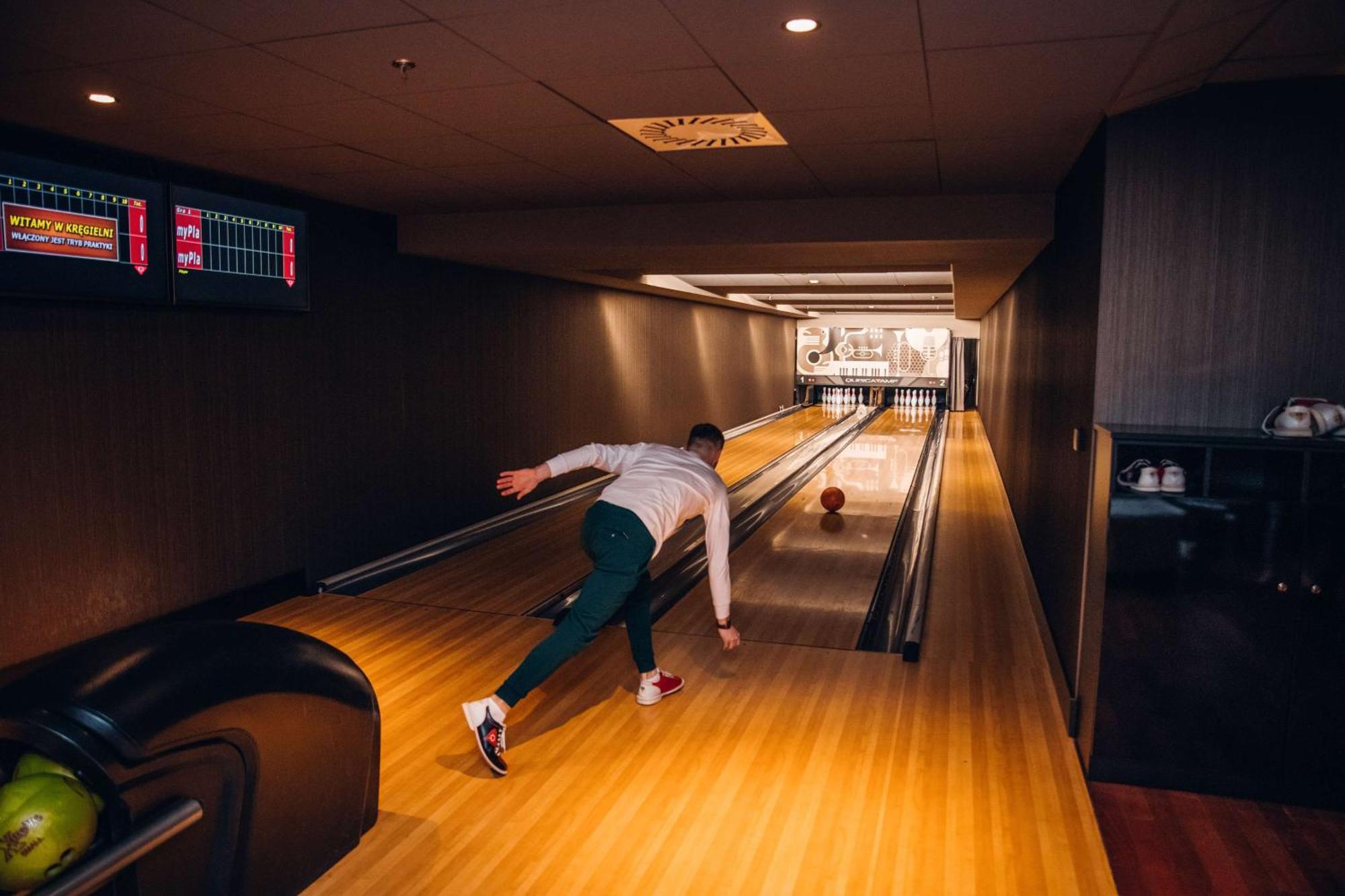 Radisson Blu Resort Swinoujscie Luaran gambar The photo shows a bowling alley. In the foreground, a person is throwing a bowling ball down the lane. They are wearing a white top and green pants, with red and white shoes. The bowling lane is made of polished wood, and at the end of the lane, ther