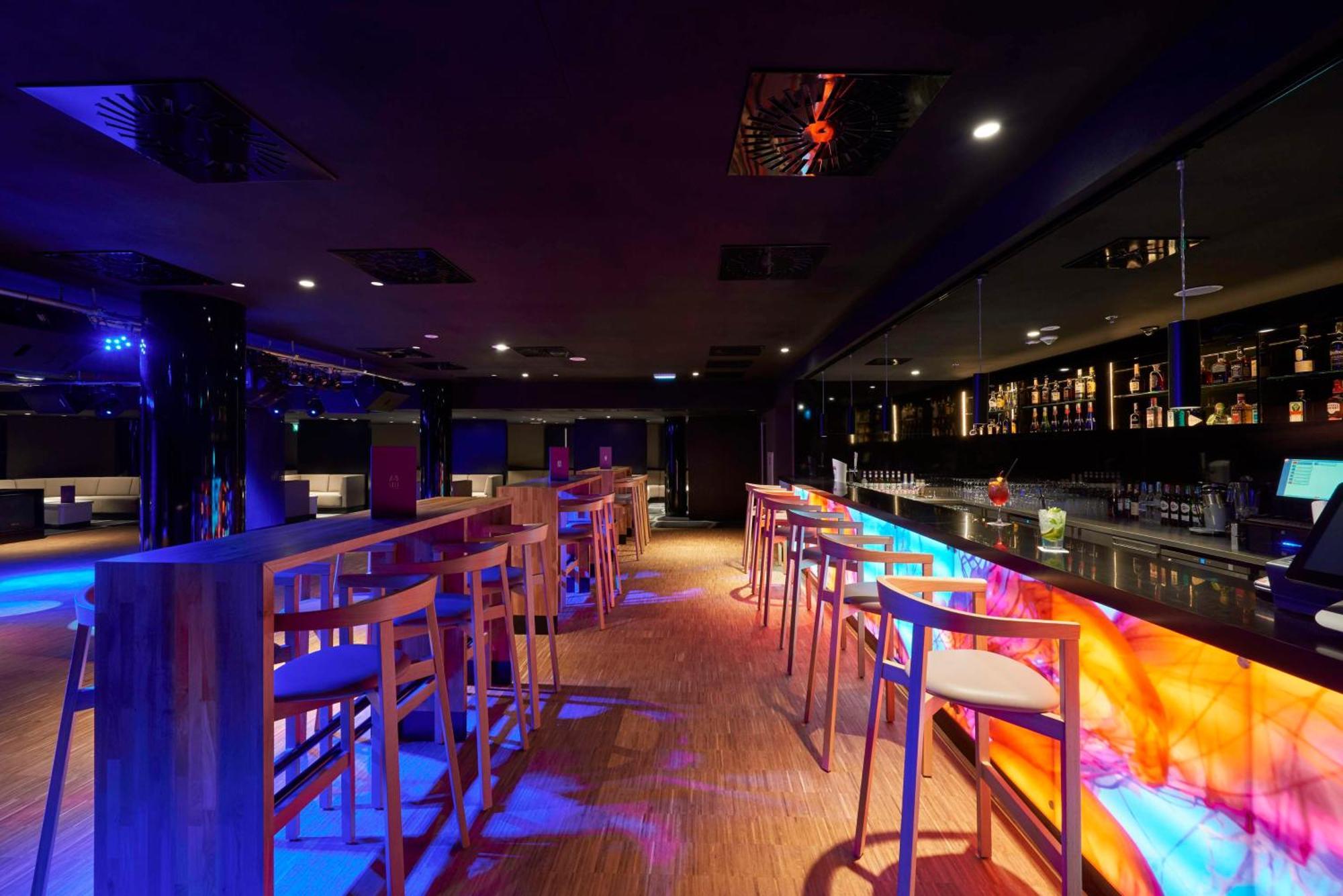 Radisson Blu Resort Swinoujscie Luaran gambar The photo depicts a modern bar interior with a sleek and contemporary design. There are high wooden stools positioned along a bar counter, which features vibrant, colorful lighting underneath. The bar area is dimly lit, creating a nightlife ambiance,