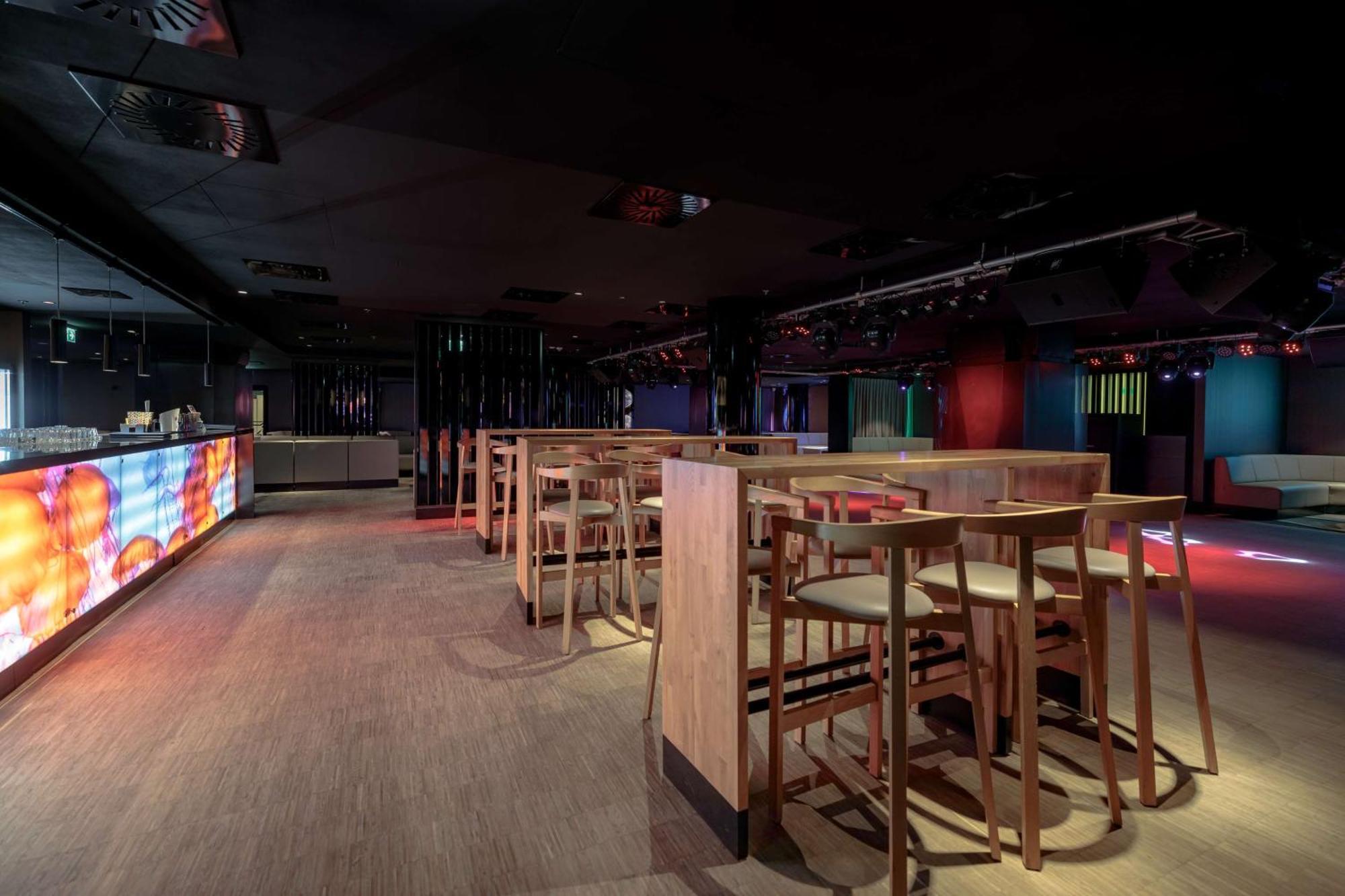Radisson Blu Resort Swinoujscie Luaran gambar The photo shows an interior space that appears to be a bar or lounge. It features a modern design with a dark color scheme. There are several wooden high-top tables with matching stools arranged in the area. In the background, there is a bar counter,