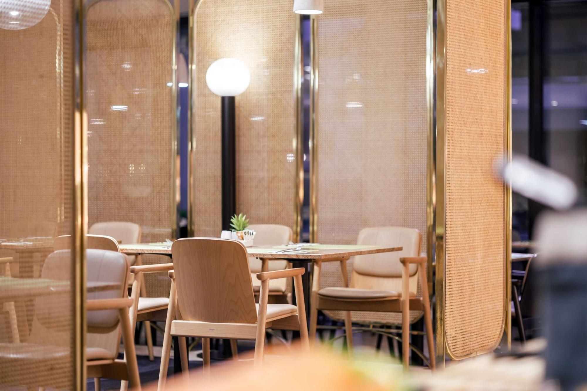 Radisson Blu Resort Swinoujscie Luaran gambar The image shows an interior space, likely part of a restaurant or café. There are several wooden chairs arranged around tables, and the overall decor features soft lighting and warm colors. The walls appear to be partially covered with a woven materi