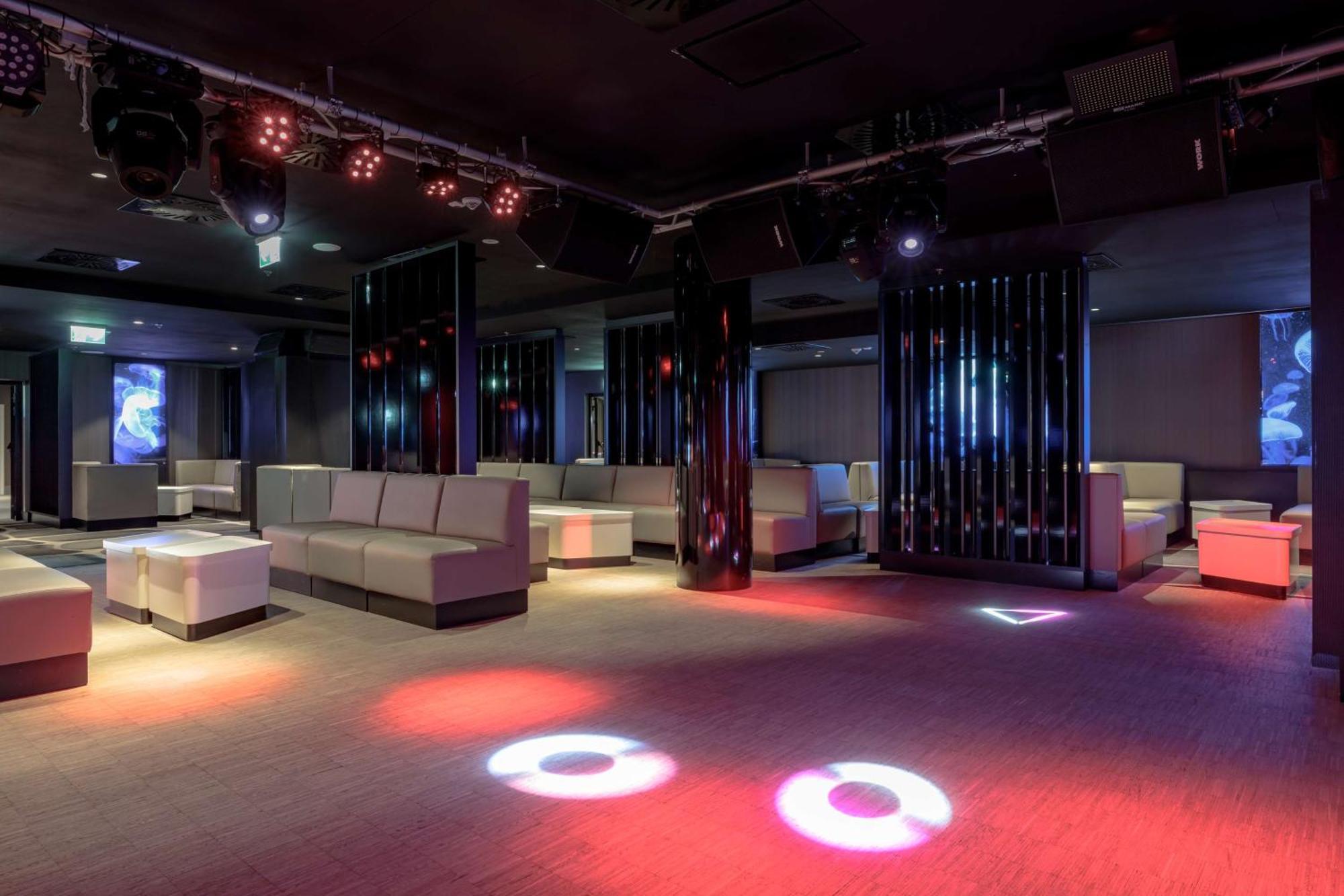 Radisson Blu Resort Swinoujscie Luaran gambar The photo depicts a modern nightclub interior, featuring a spacious layout with sleek, minimalist seating arrangements. The room has plush seating along the walls, and the floor is illuminated with circular lights in varying colors, creating a vibran