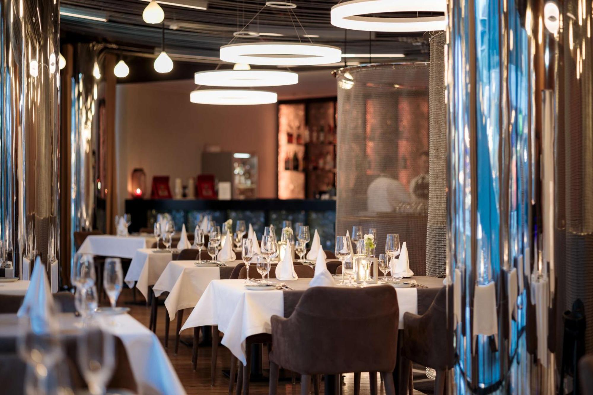 Radisson Blu Resort Swinoujscie Luaran gambar The photo depicts an elegant restaurant interior. There are several tables covered with white tablecloths, each set with glassware and napkins, suggesting a fine dining experience. The chairs are upholstered, providing a comfortable seating arrangeme