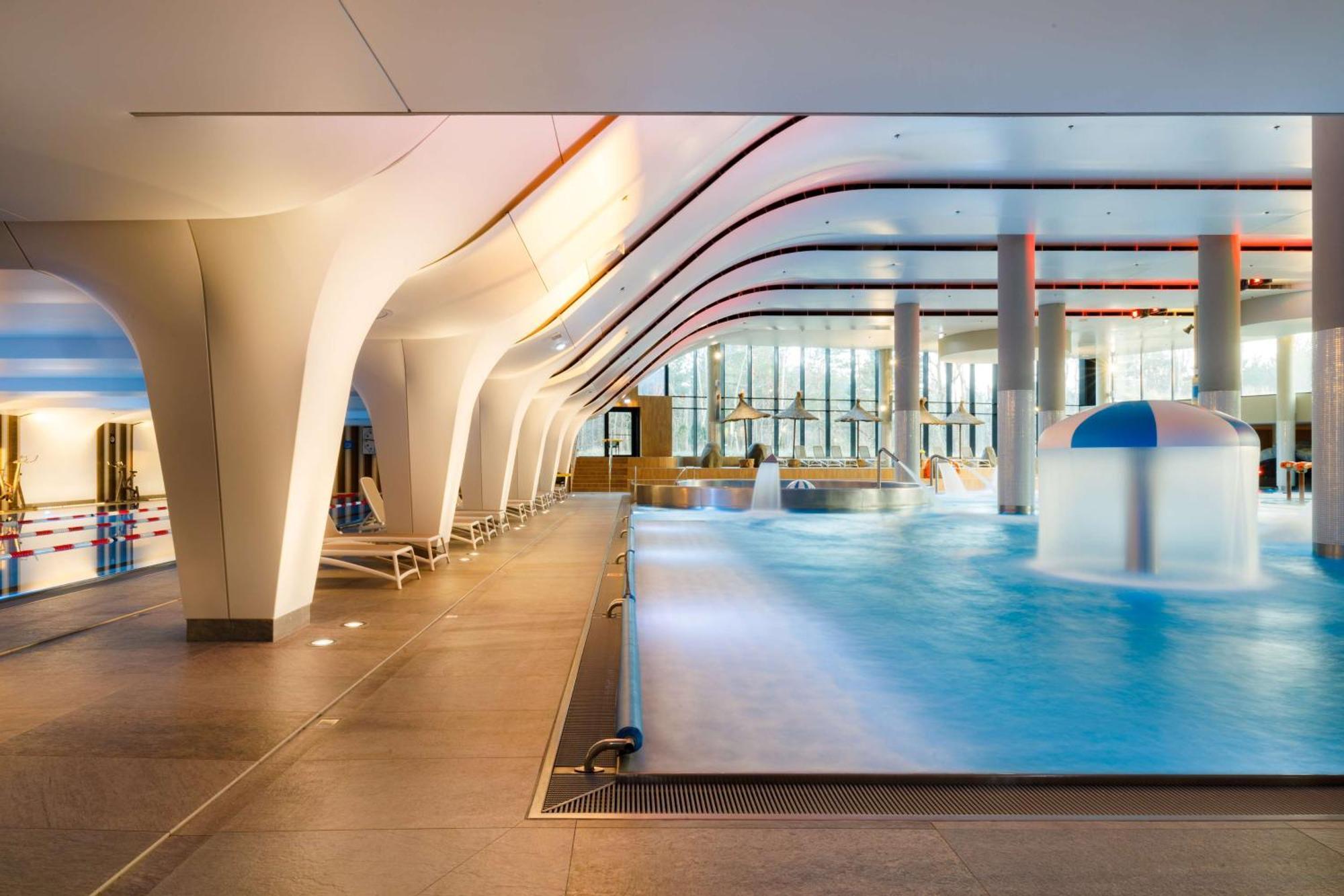 Radisson Blu Resort Swinoujscie Luaran gambar The photo shows an indoor swimming pool area with a modern architectural design. The space features large windows allowing natural light to enter, and the interior has smooth, flowing lines in the ceiling and columns. The pool has a light blue water 