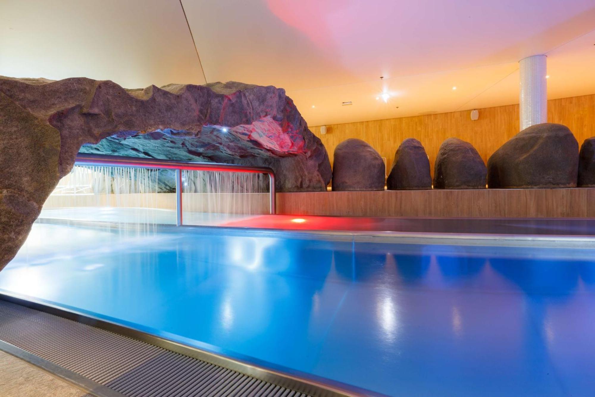 Radisson Blu Resort Swinoujscie Luaran gambar The photo shows a serene indoor swimming pool area. The pool has clear blue water, and there is a distinctive rock formation that resembles a cave on one side. Soft lighting enhances the atmosphere, casting a gentle glow across the space. In the back