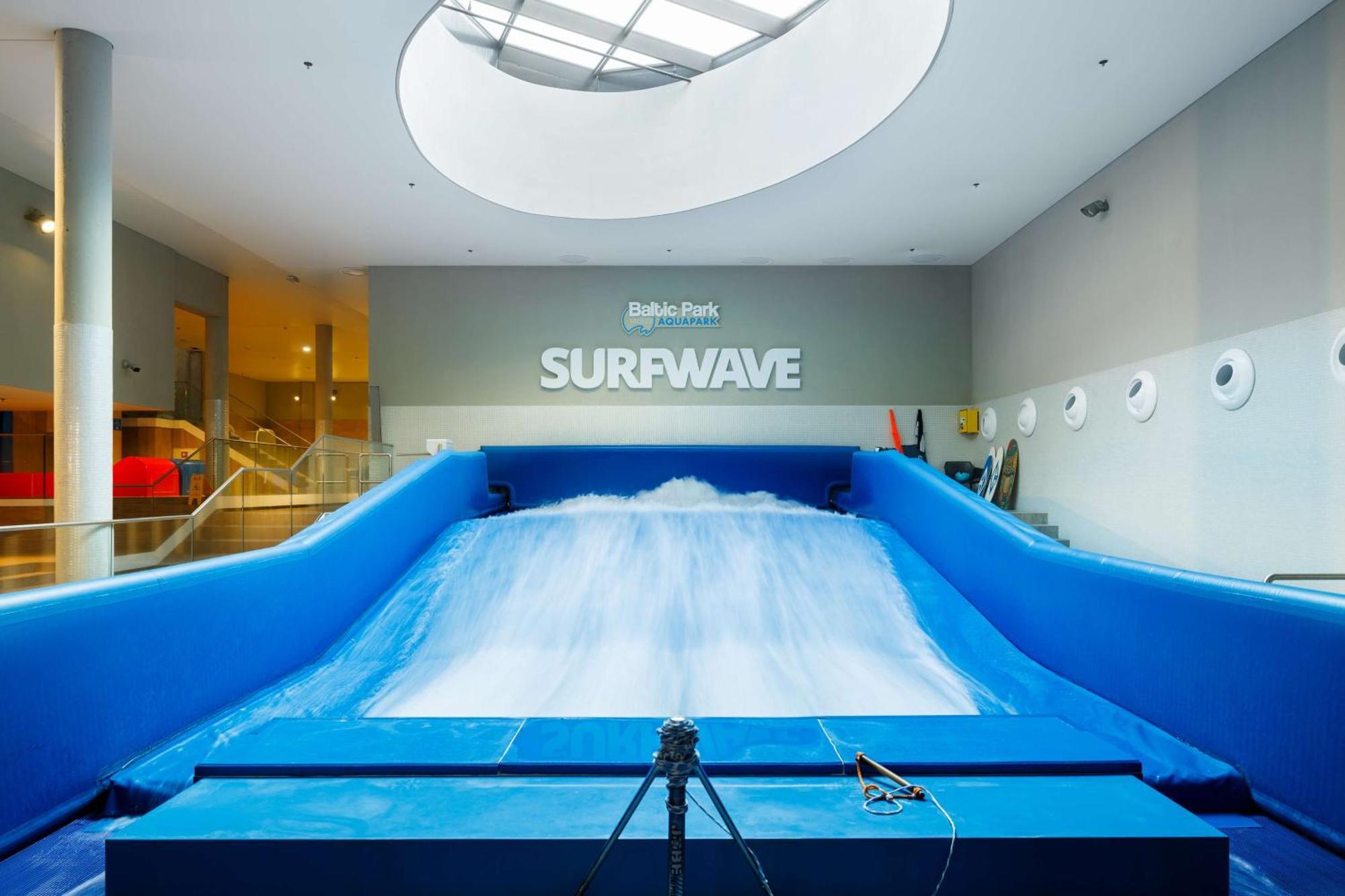 Radisson Blu Resort Swinoujscie Luaran gambar The photo shows an indoor surfing attraction called "Surfwave." It features a large blue ramp with water flowing down it, creating a wave-like effect for surfing. Above the ramp, there is a sign that says "SURFWAVE." The area appears well-lit and mod